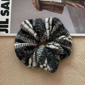Gros plan d'un chouchou en grosse maille tricotée à rayures noires et grises douces