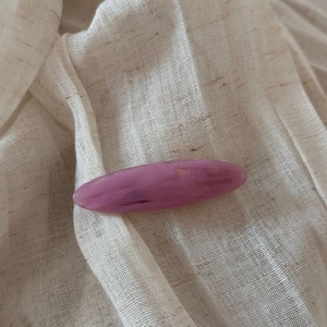 Detailed macro of handmade purple tortoiseshell acetate hair clip on beige linen