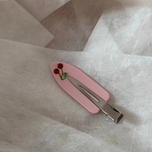 Detail of a pink duckbill hair clip featuring red 3D cherry and green leaf accents