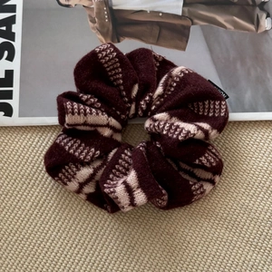 Gros plan détaillé du chouchou en tricot épais à rayures bordeaux et crème sur tapis