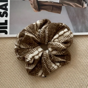 Détail montrant la texture douce en tricot et le motif rayé d'un chouchou marron géant