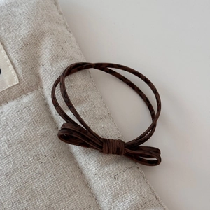 Detail of dark brown leopard print hair tie with double strands and minimalist bow