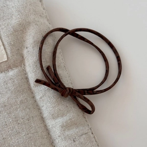 Detail of dark brown leopard print hair tie with elastic cord and bow knot design