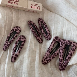 Dettaglio di fermagli per capelli con stampa leopardata rosa su lino beige morbido