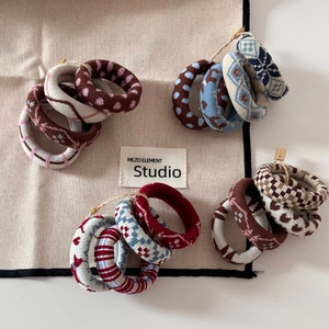 Detailed overhead view of assorted patterned jacquard elastic hair ties on studio fabric
