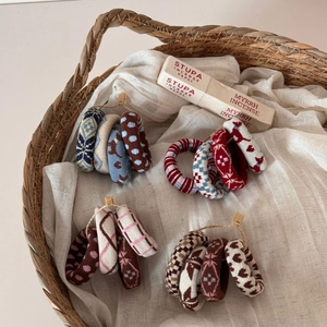 Detailed close-up of knitted scrunchies with ethnic patterns in a wicker basket