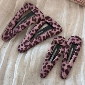 Dettaglio di quattro fermagli per capelli con stampa leopardata viola su lino strutturato