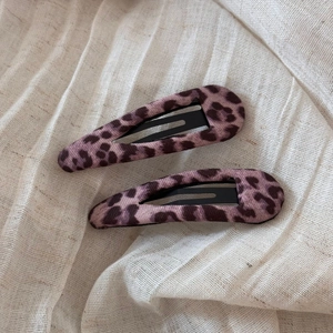 Dettaglio di fermagli BB a goccia con tessuto leopardato rosa e base in metallo nero