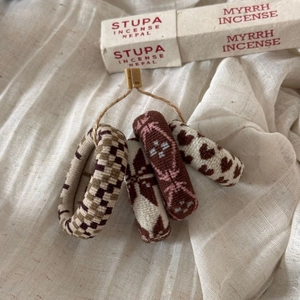 Detailed view of four jacquard knit hair scrunchies in earth tones on white linen fabric