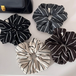 Detail view of four striped knitted scrunchies in black, gray, coffee, and beige colors