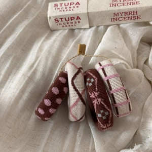 Close-up of four knitted elastic hair ties with patterns on a textured fabric background