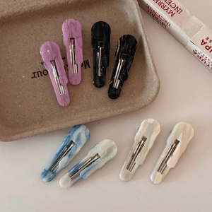 Detailed view of acetate hair clips in marble and solid tones with metal duckbill clips