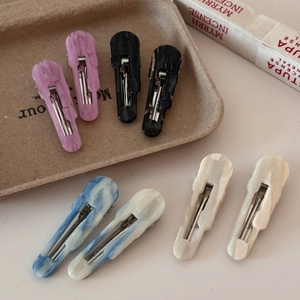 Detail of elegant acetate hair clips with marble patterns on a rustic paper tray