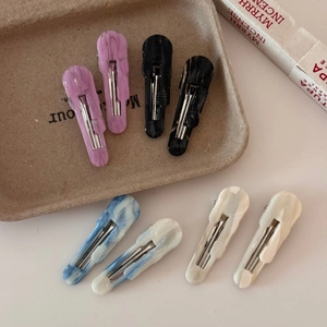 Close-up of acetate duckbill hair clips in marble and solid patterns with metal springs