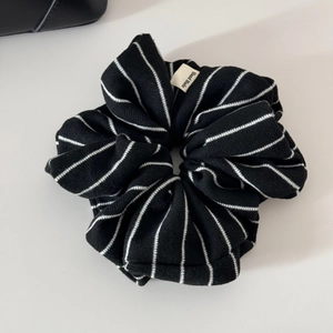 Detail of a black and white striped cotton scrunchie with a Hand Made fabric label