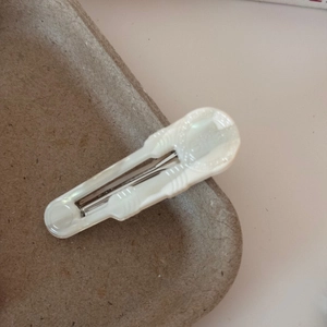 Close-up of a pearlescent white acetate duckbill hair clip with embossed vintage texture