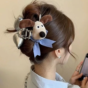 Dettaglio di fermaglio per capelli cane in peluche con fiocco blu e clip in metallo