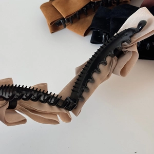 Detail view of multi-layer suede bow banana clip showing inner plastic grip teeth