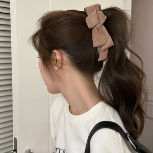 Detailed close-up of brown suede multi-layered bow banana clip on high ponytail