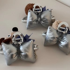Dettaglio macro di teste di cuccioli in peluche e fiocchi argentati sulle pinze per capelli