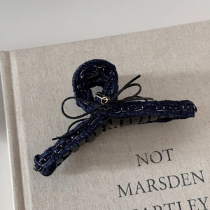 Detail of dark blue denim hair claw clip with black leather bow and white contrast stitching