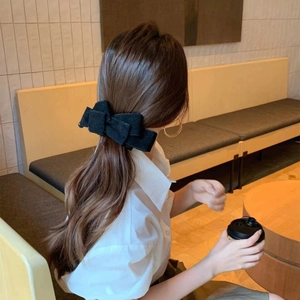 Detail of elegant black velvet multi-layer bow banana clip worn on low ponytail hairstyle