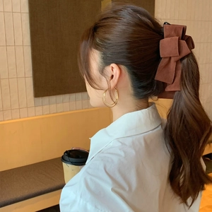 Elegant brown suede multi-layered bow hair clip worn on a low ponytail ponytail holder
