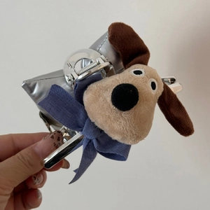 Dettaglio della molletta per capelli a cane in peluche con fiocco blu e texture argento