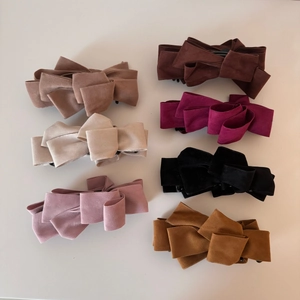 Detailed macro view of multi-layered suede bow hair clips in seven elegant assorted colors