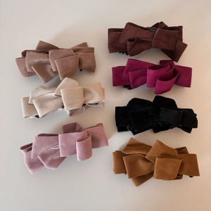 Macro view of multi-layered faux suede bow banana hair clips in seven autumn-inspired colors
