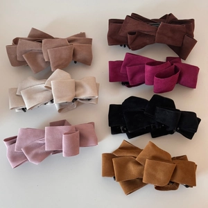 Macro detail of multi-layered faux suede bow hair clips in seven elegant assorted colors
