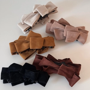 Macro shot of multi-layered suede bow hair clips in five elegant pastel and earthy colors