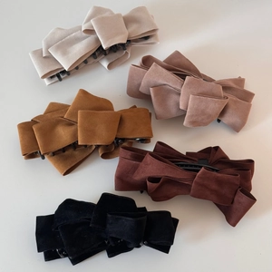 Detail of five multi-layered faux suede bow banana clips in various earth-tone colors