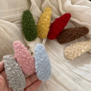 Macro view of colorful plush teardrop hair clips set in cozy lamb wool texture