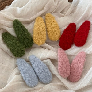 Detailed macro view of colorful lamb wool plush hair clips in five soft pastel shades