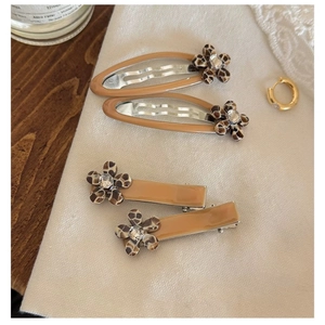 Detail of leopard print flower hair clips with rhinestones on beige fabric and wood