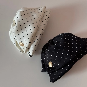 Détail de pinces à cheveux à pois en soie avec un badge en métal doré gravé élégant