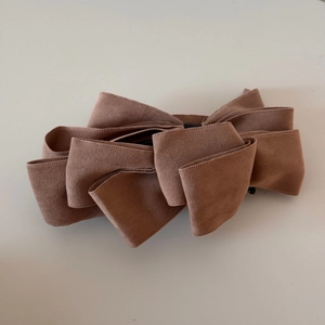 Detailed view of large multi-layer mocha suede bow hair clip with elegant fabric texture