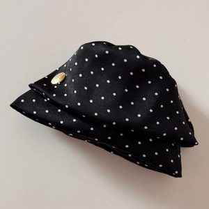 Détail d'une pince à cheveux noire à pois blancs avec un label métallique doré élégant
