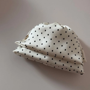 Vue détaillée de la pochette vintage en satin à pois avec un bouton pression doré