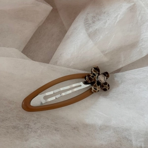 Detail of tortoise shell floral hair clip with leopard print and sparkling crystal center