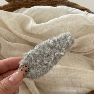Close-up of a soft grey plush fleece hair clip with warm autumn texture and oval design