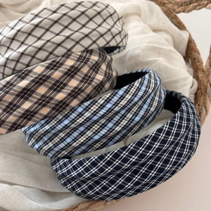 Close-up of four plaid fabric headbands in a woven basket with soft lighting