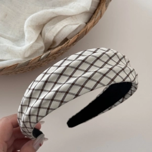 Detail of a plaid wide headband showing textured fabric and black non-slip inner lining
