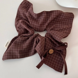 Close-up of brown plaid scrunchie with a wooden button and bow tie detail