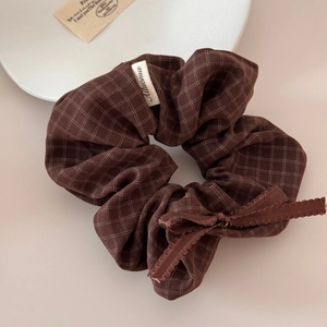Detail of coffee plaid scrunchie with bow tie and fabric texture in close-up view