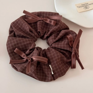 Close-up of brown plaid hair scrunchie with satin bows on a minimalist background
