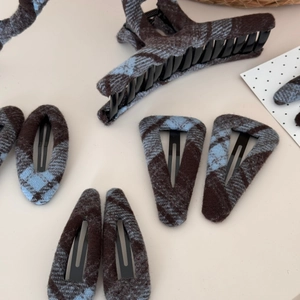 Detailed view of blue plaid fabric hair claw and assorted clips with wool texture