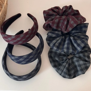 Close-up detail of plaid hairbands and scrunchies in burgundy, navy, and green fabrics