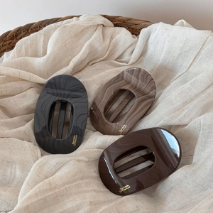 Détail de trois barrettes en acétate aux motifs de marbre et vagues dans les tons terre